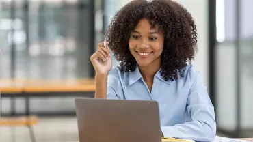 Personne souriante utilisant un ordinateur portable à un bureau.
