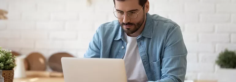 Personne travaillant sur un ordinateur portable à une table.